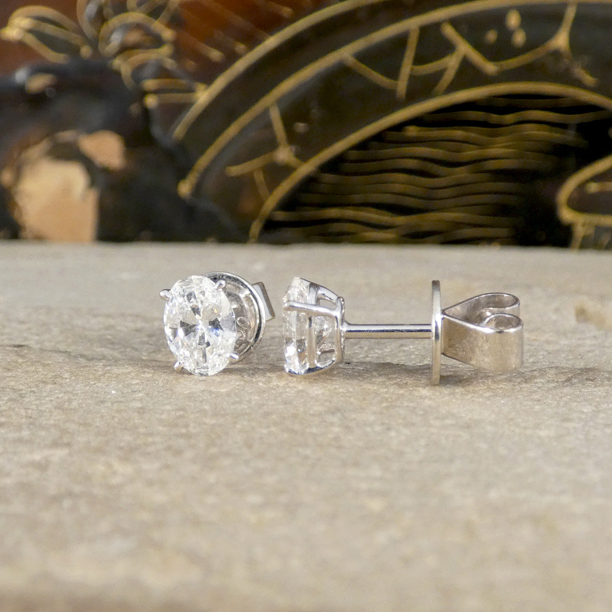 White Gold earrings on a textured surface with a decorative background