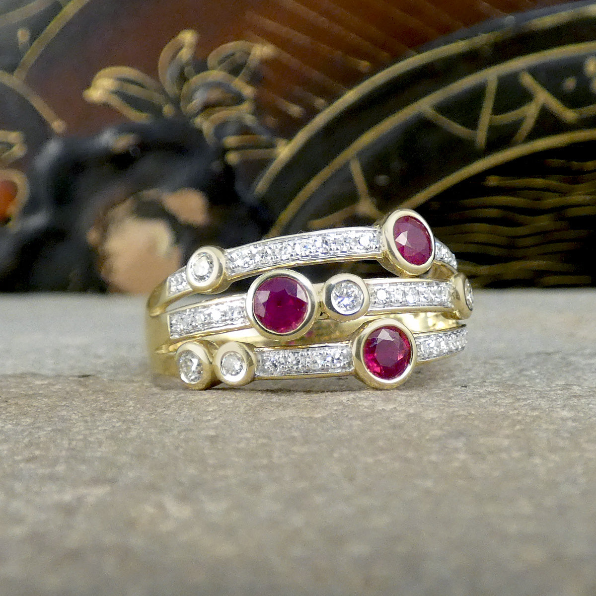 Rubies set into  rub over bezel setting in yellow gold, one on each strand of the bubble ring with Diamonds set the same and further diamond set into the band.