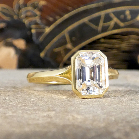 1.55ct Emerald Cut Diamond Solitaire in a Bezel Setting in 18ct Yellow Gold, showcasing a clear and bright diamond graded F/VS