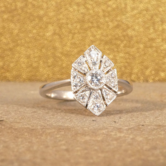 Art Deco-inspired replica ring crafted with exquisite craftsmanship in 18ct white gold, featuring intricate geometric patterns and a central diamond accent.