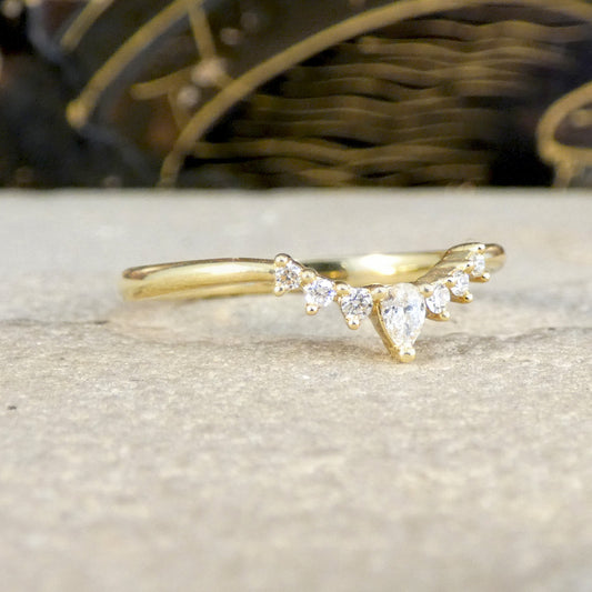 Gold ring with pear-shaped diamonds on a textured surface