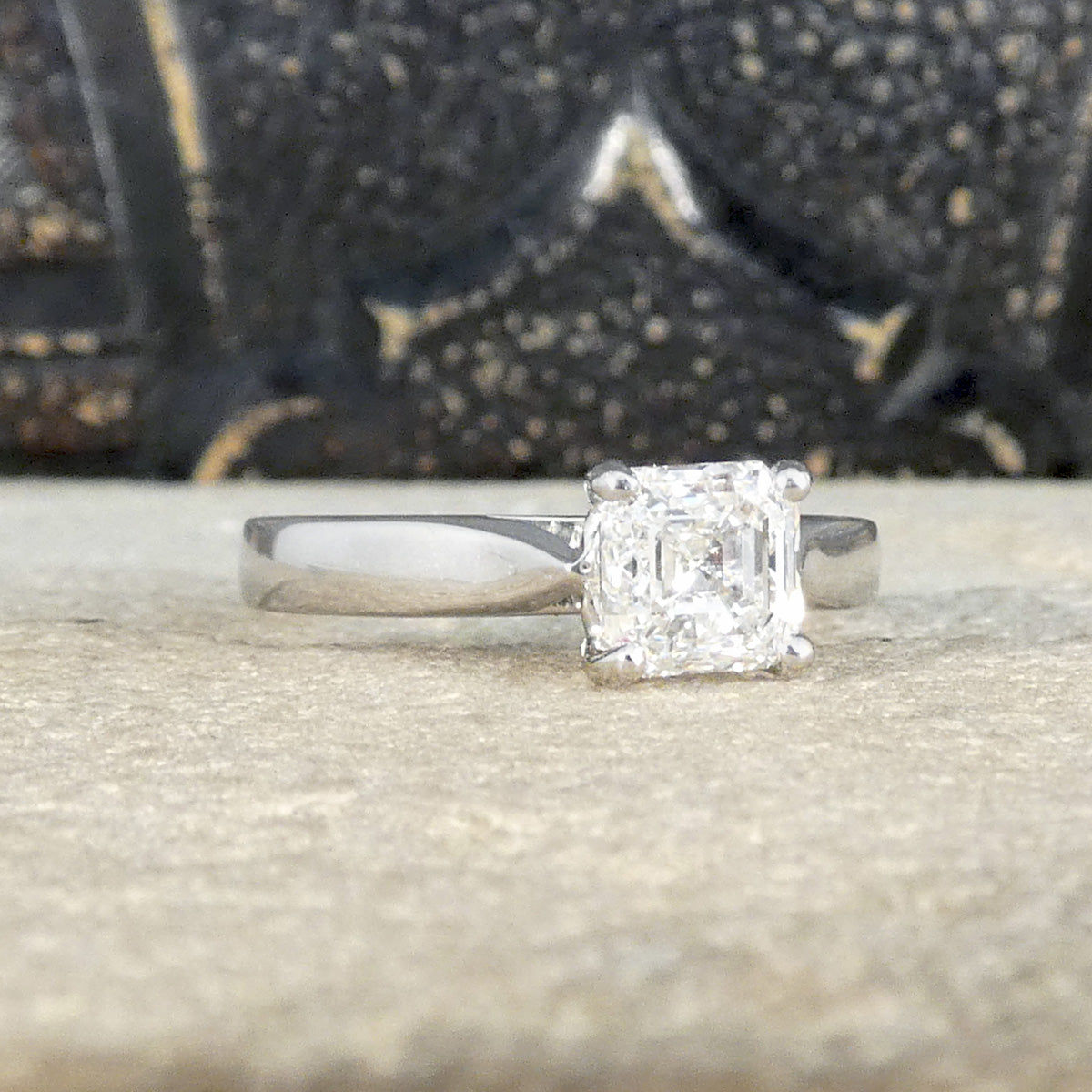 A Squared Emerald Cut Diamond Solitaire Engagement Ring in a four claw setting with a chunky Platinum band and modern feel. Bright Diamond with a GIA certificate.