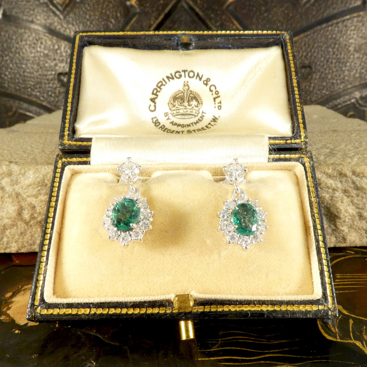 A beautiful pair of Oval Cut Emeralds surrounded by a halo of bright and sparkly diamonds hanging from a diamond stud as a drop earrings. Fully crafted in 18ct White gold, making the perfect gift.