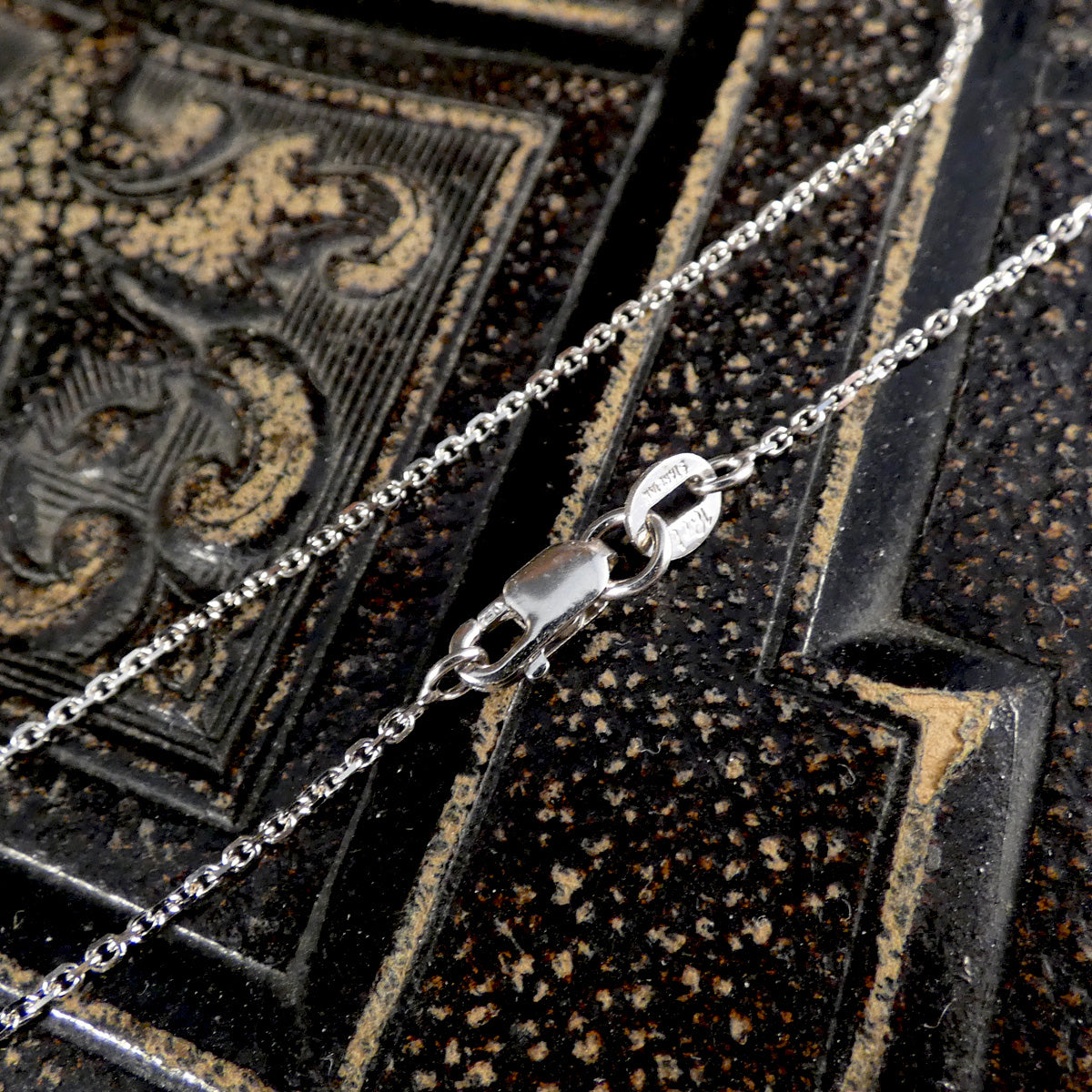Close-up of a 18ct white gold chain on an ornate black and gold background