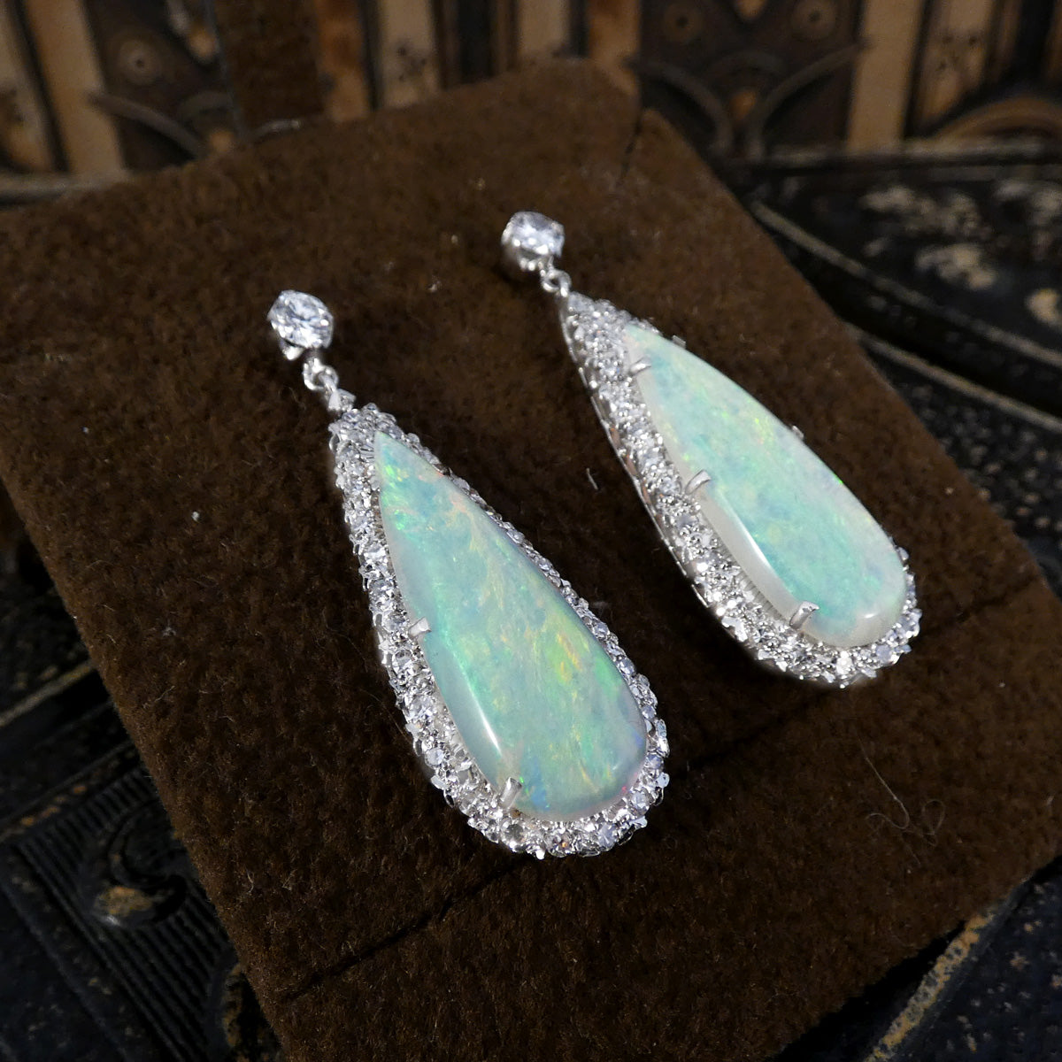 Elegant vintage opal and diamond cluster drop earrings in platinum, featuring pear-shaped opals surrounded by halos of brilliant diamonds and secured with round diamond studs.