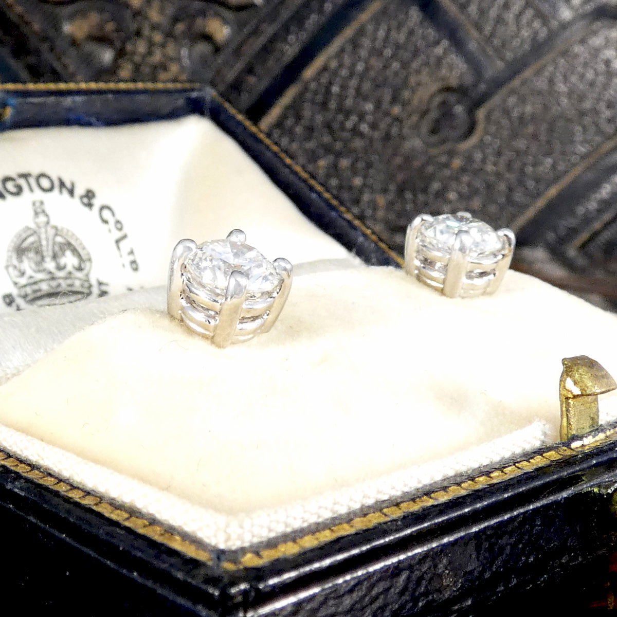 Diamond earrings in a black and gold jewellery box.