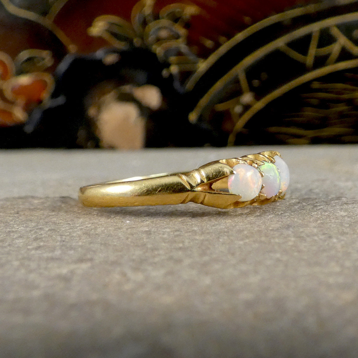 Gold ring with opal stones on a textured surface