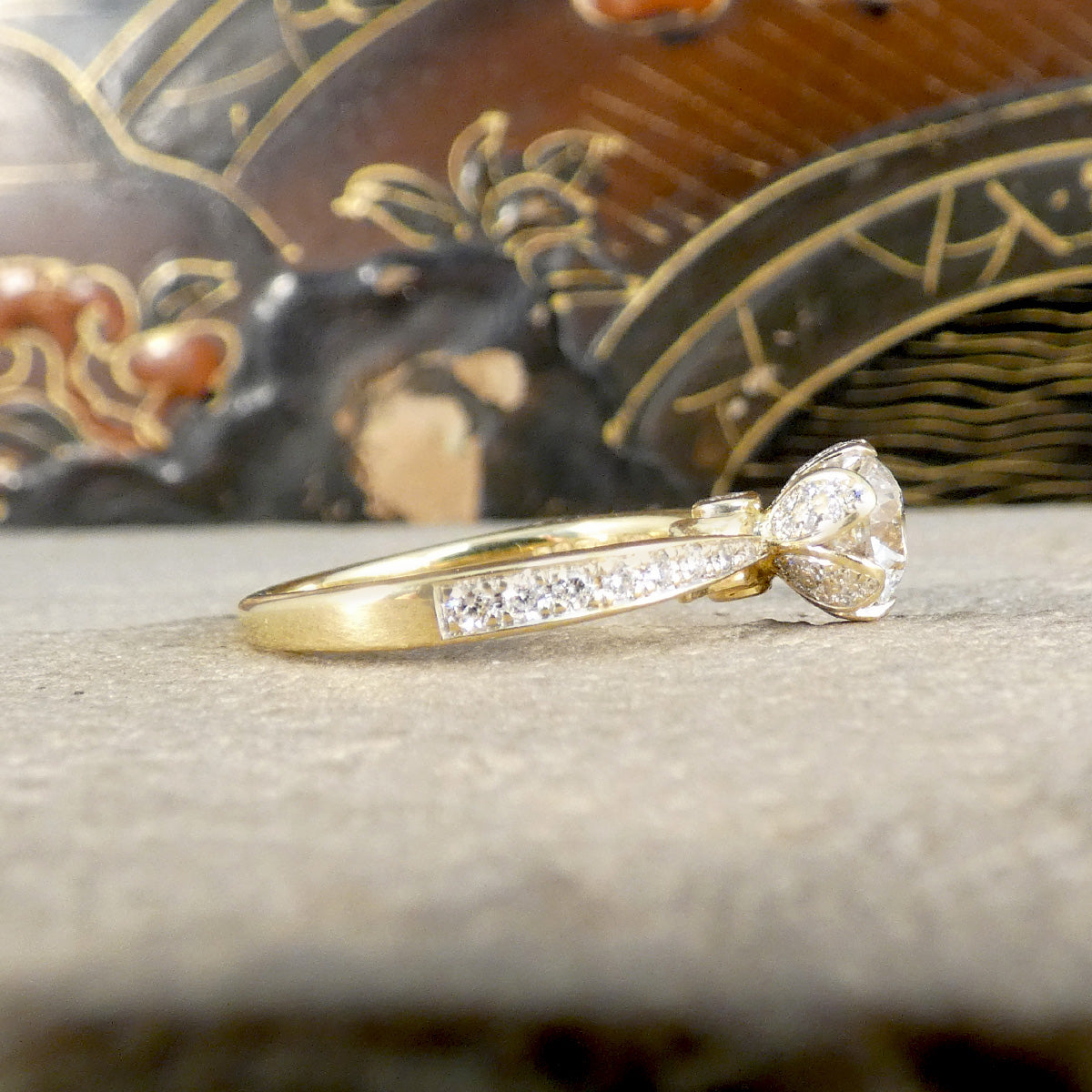 Gold ring with a diamond bow design on a textured surface