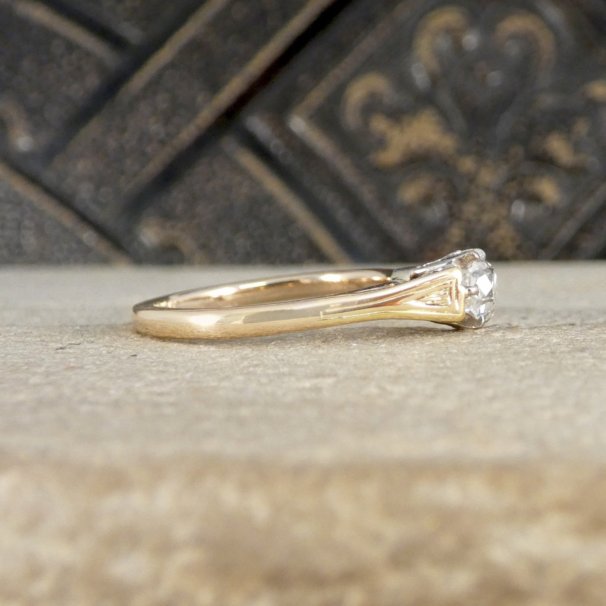 Gold ring with a diamond on a textured surface with a decorative background