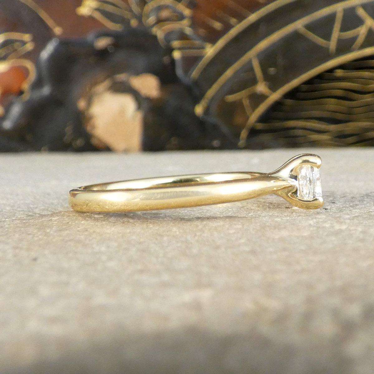 Side profile view of an 18-carat yellow gold solitaire ring featuring a GIA-certified modified cushion-cut diamond of E colour. The sleek and minimalist band showcases the diamond’s brilliance with a classic prong setting, emphasising timeless elegance.