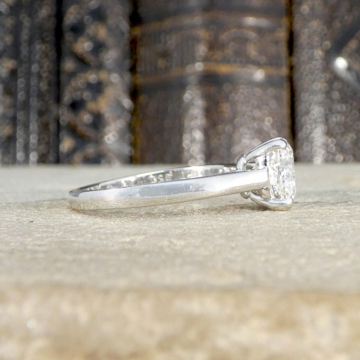 Platinum ring with a diamond on a textured surface shown from the side showing plain polished band.
