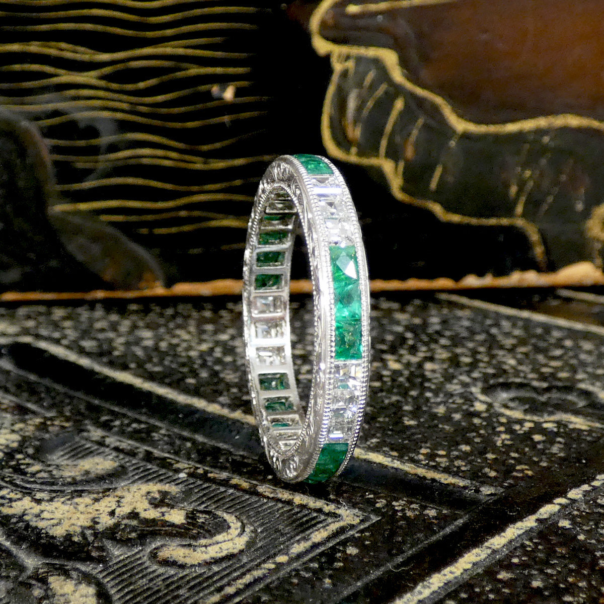 Diamond and Emerald ring stacked on its side.