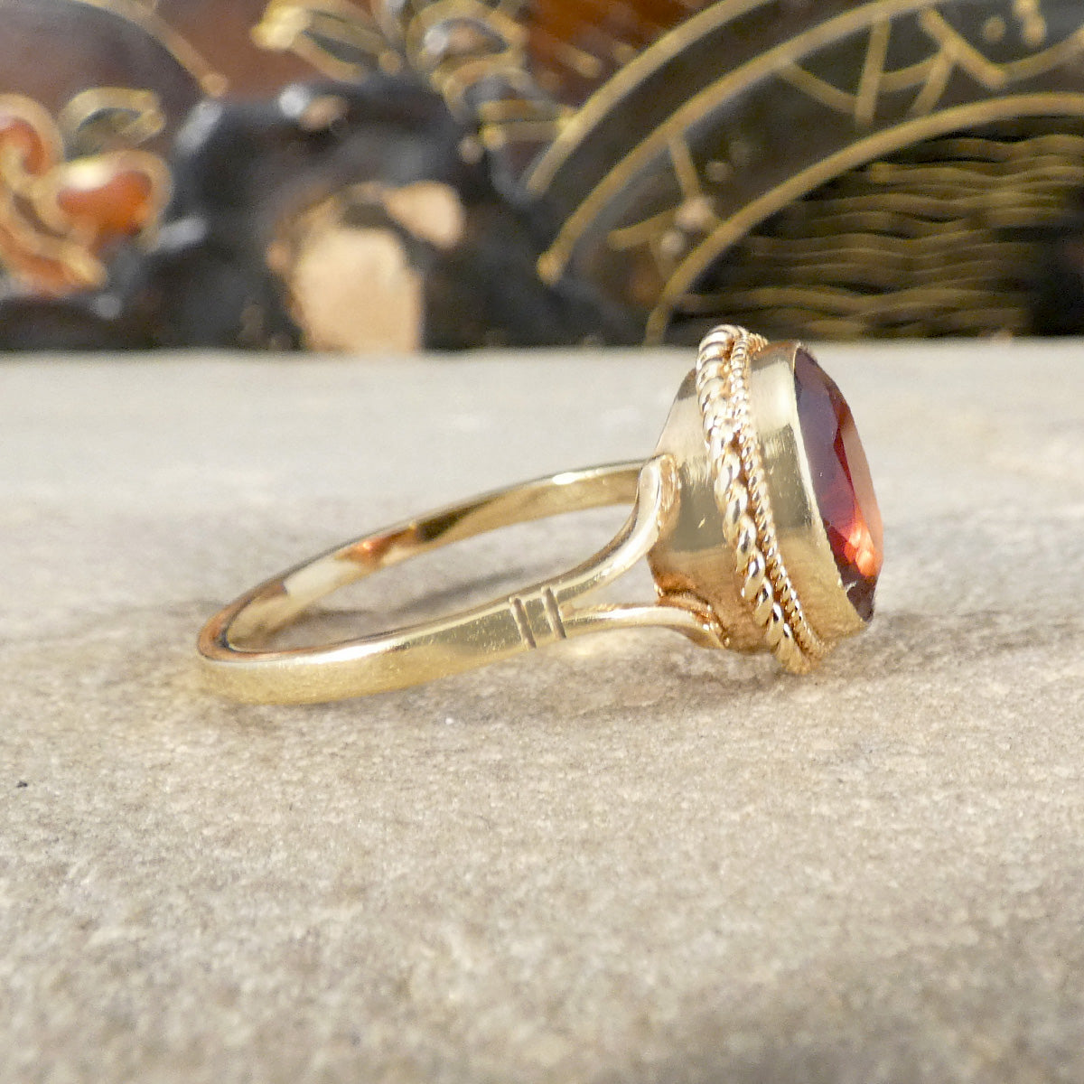 Gold ring with a red gemstone on a textured surface