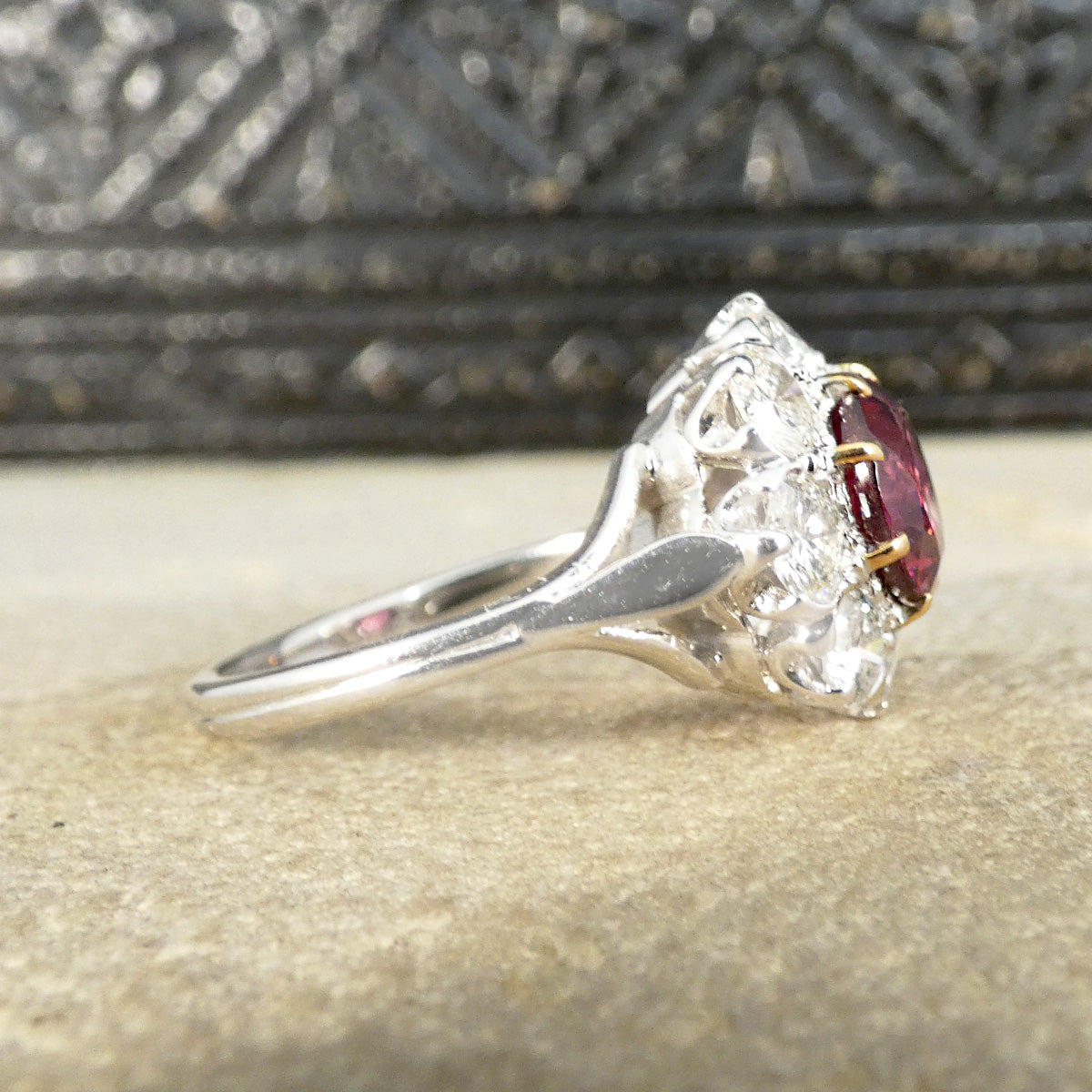Side view of 2.00ct Pyrope Garnet and 1.40ct Brilliant Cut Diamond flower cluster ring in 18ct White Gold with Yellow Gold claws on the Garnet. Showing slight detail on band.