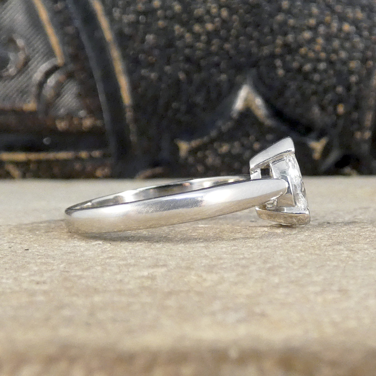 Side view of pear cut solitaire diamond ring with substantial and polished platinum band.