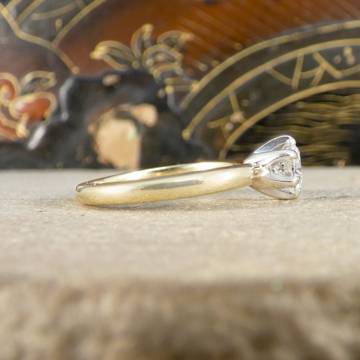 Gold ring with a diamond on a textured surface with a decorative background