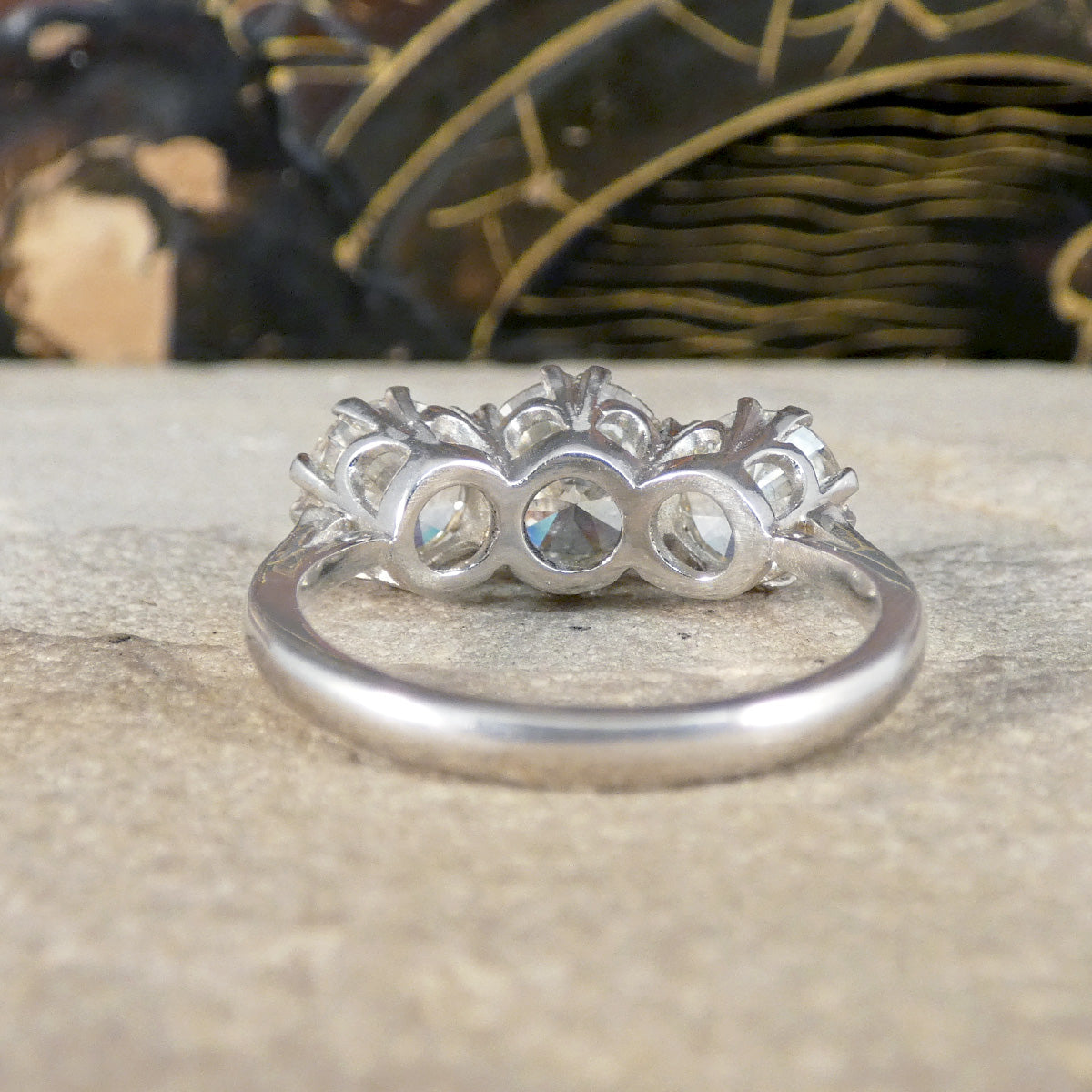Well matched diamond three stone ring shown from behind to see the detail and open setting allowing light to pass through.