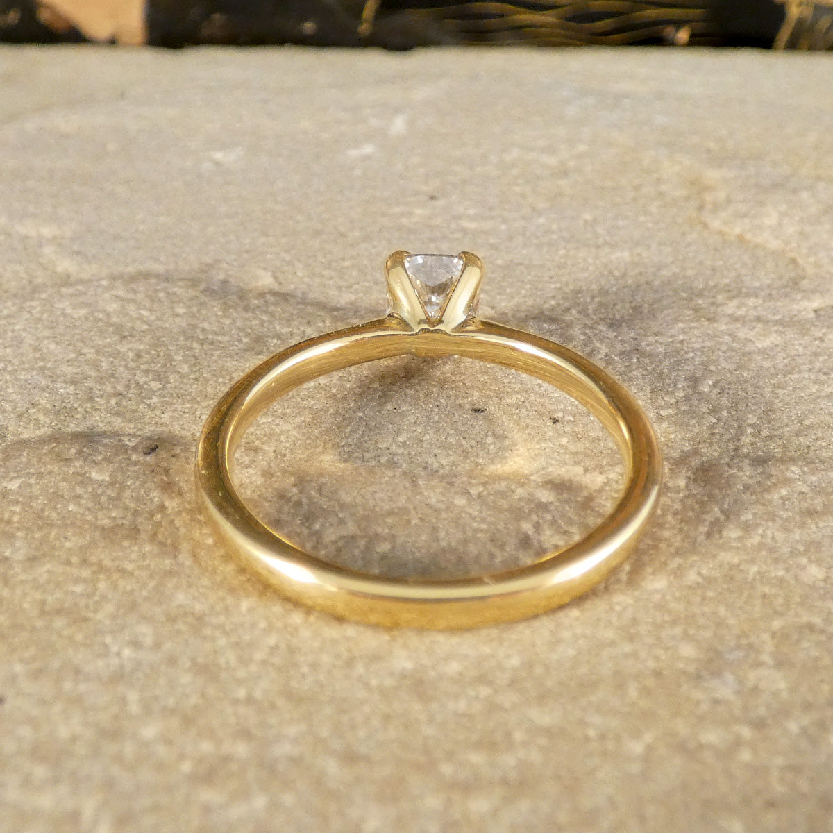 Rear view of an 18-carat yellow gold solitaire ring showcasing a GIA-certified modified cushion-cut diamond of E colour. The elegant prong setting highlights the diamond's symmetry and brilliance, paired with a sleek and polished gold band for a timeless design.