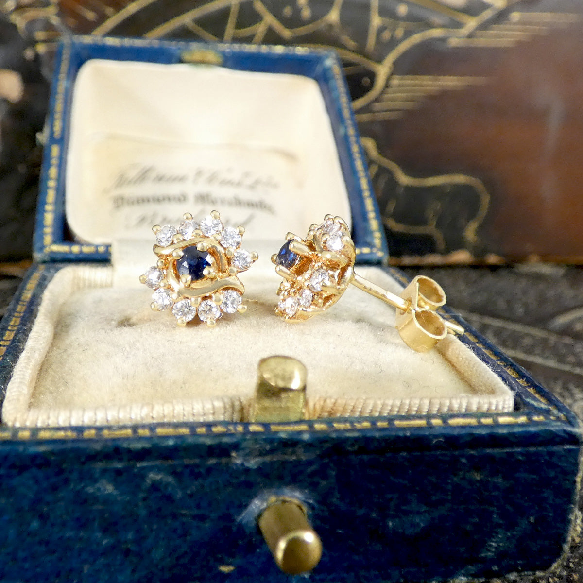 Gold earrings with blue gemstones in a blue jewelry box