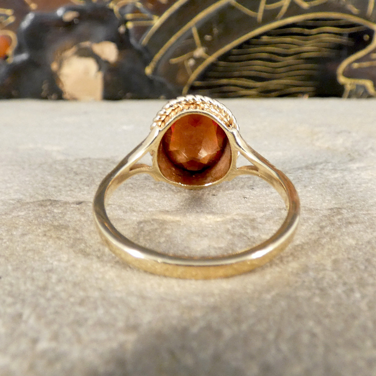Gold ring with a red gemstone on a textured surface