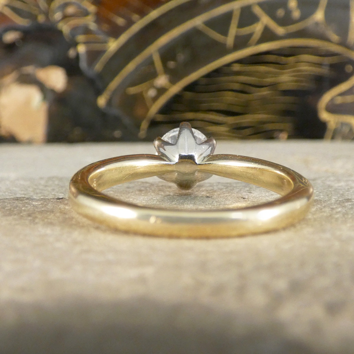 Gold ring with a diamond on a textured surface