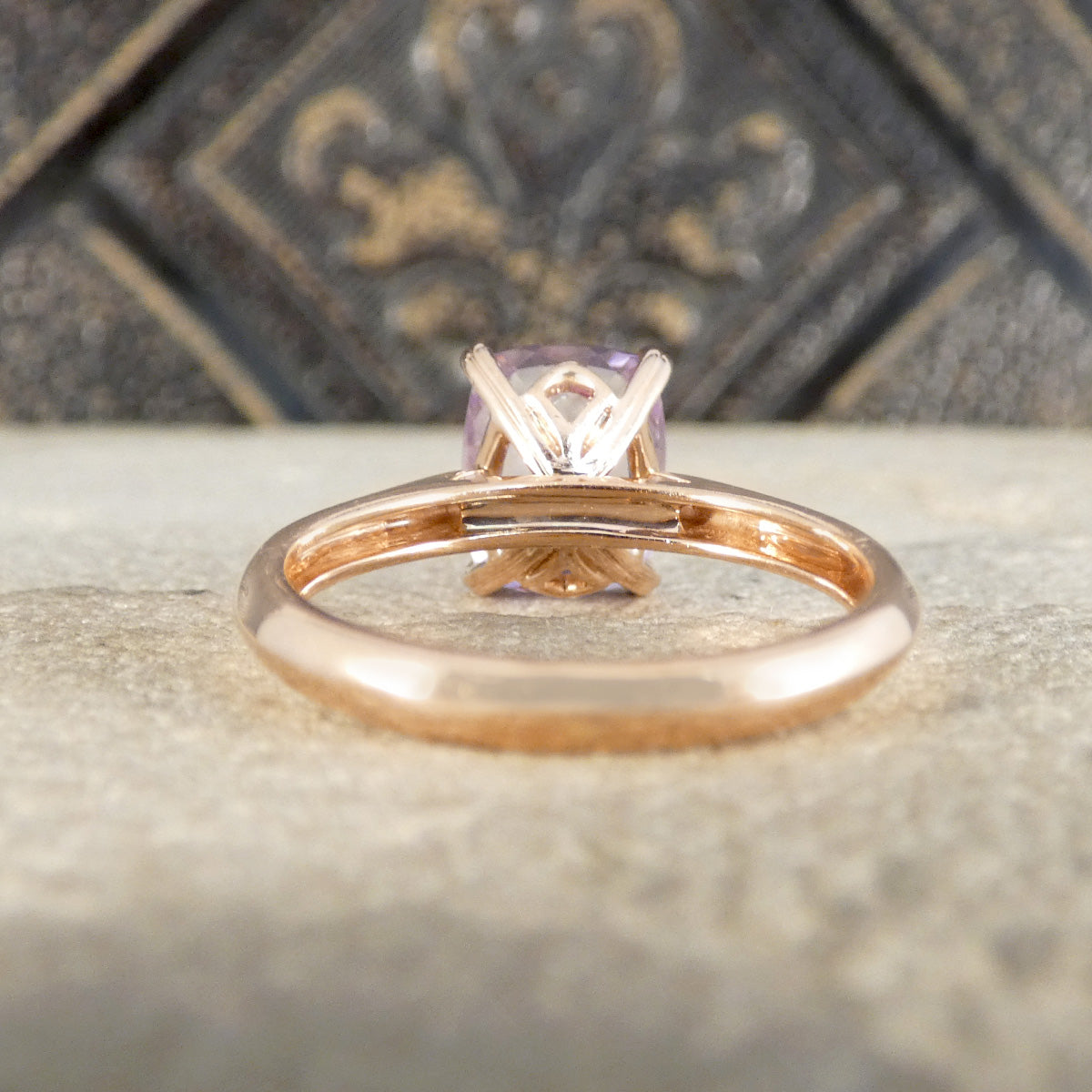Rose gold ring with an amethyst on a textured surface