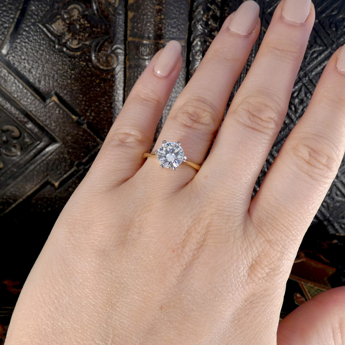 Diamond engagement ring shown displayed on the ring finger for size reference.