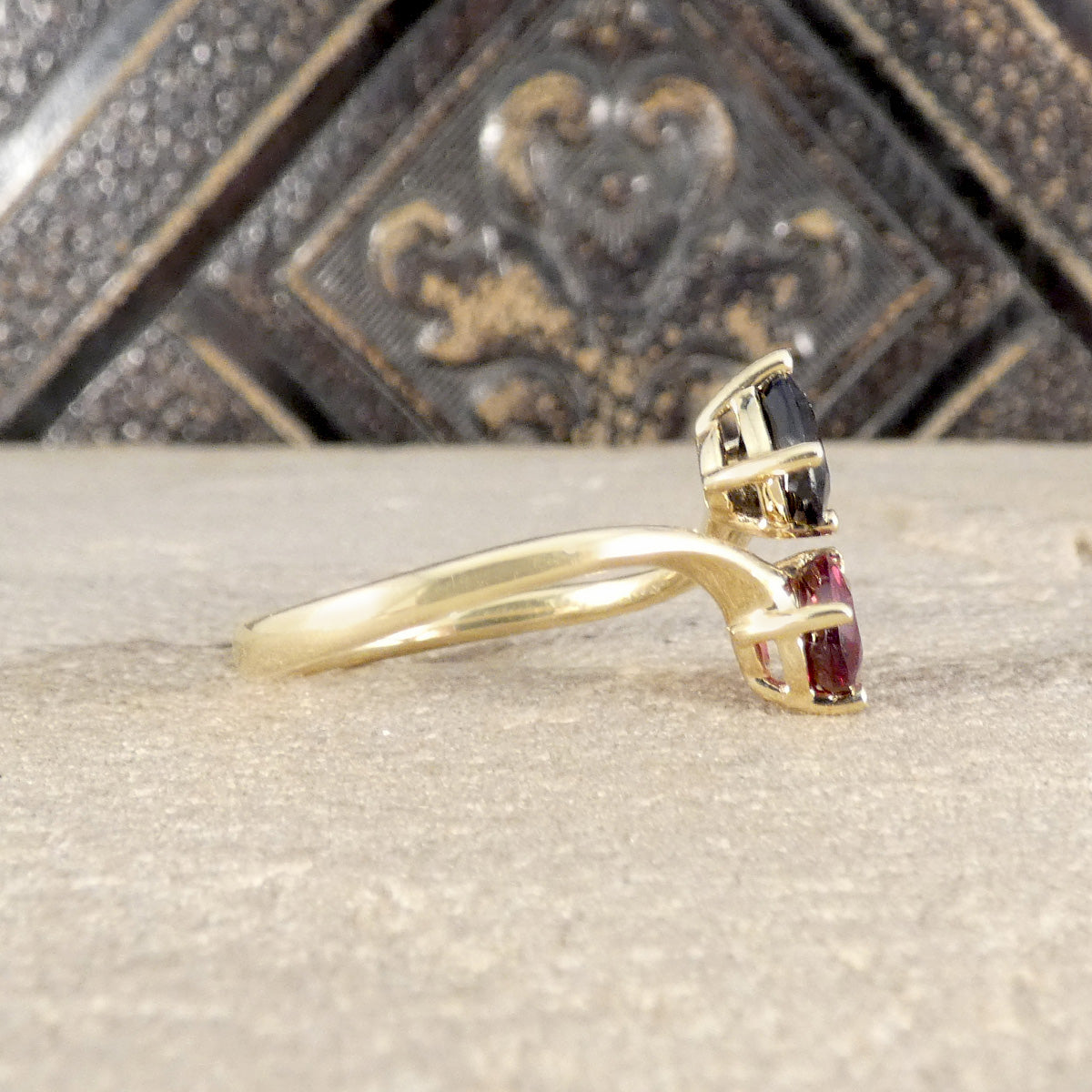 Gold ring with gemstones on a textured surface