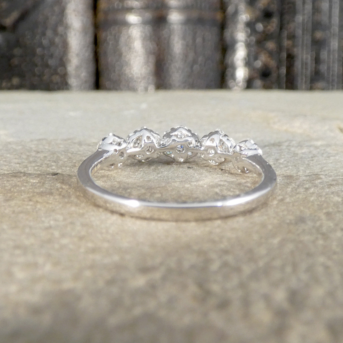 Back view of diamond five flower cluster ring showing plain polished band in white.