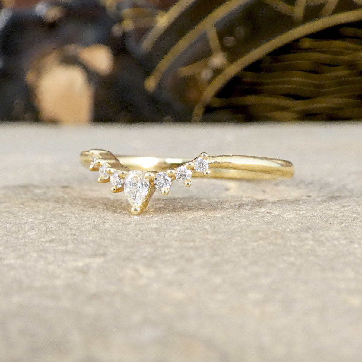 Gold ring with pear-shaped diamonds on a textured surface