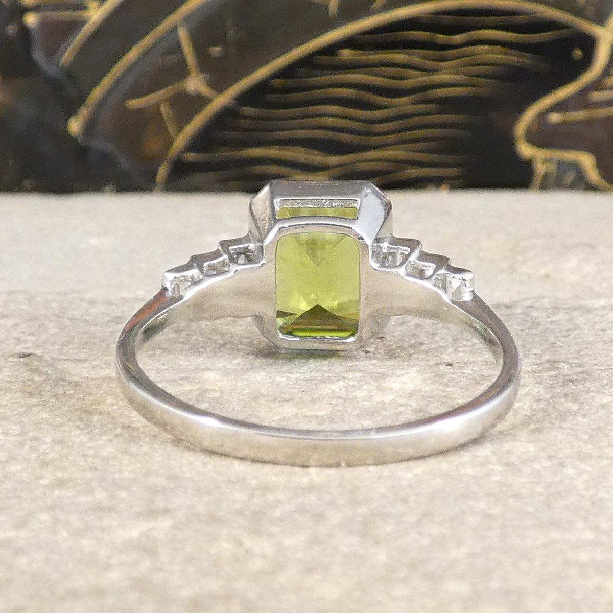 Back view of Peridot set Art deco style ring in platinum in a bezel setting with a fine band in keeping with the era.