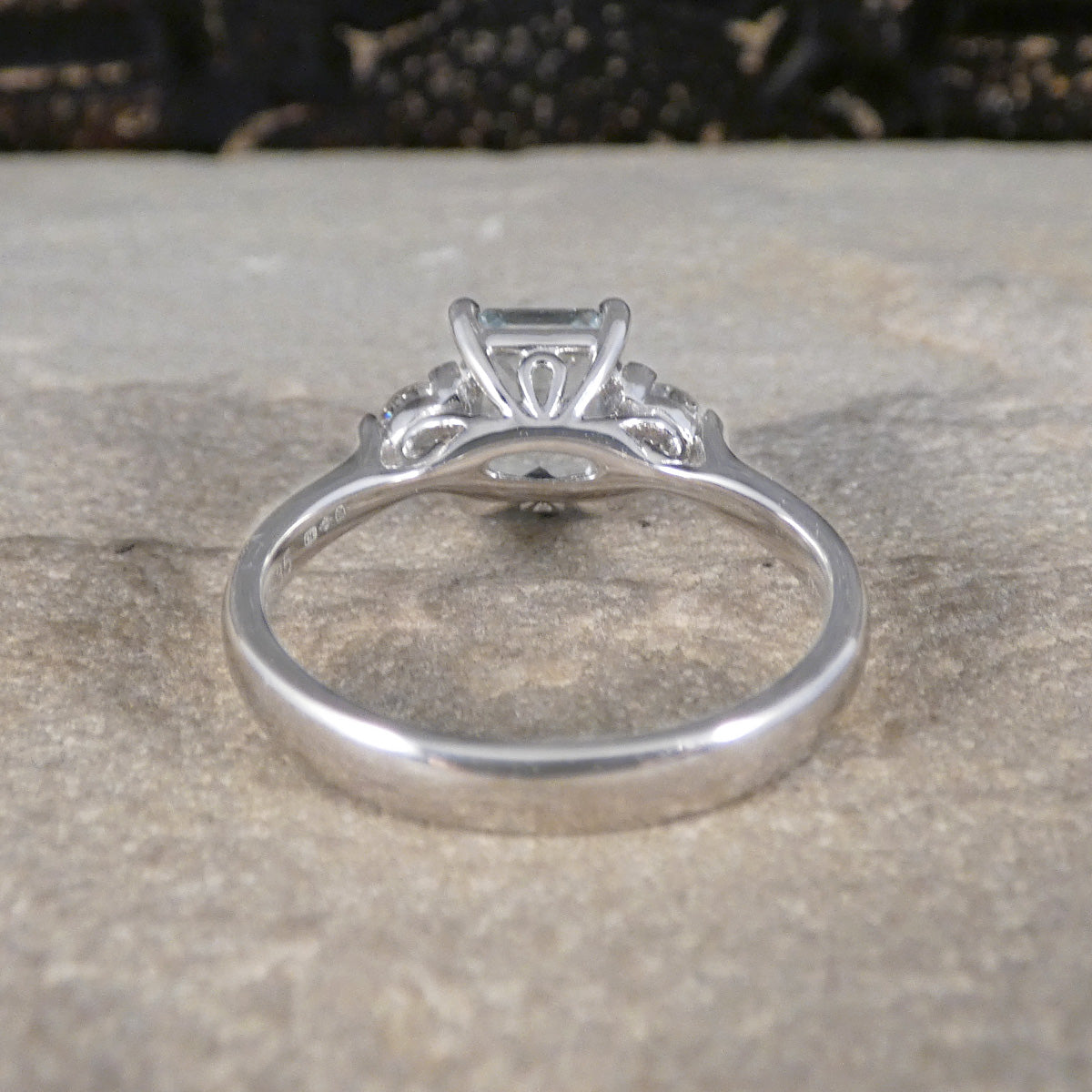 Back view of Modern Emerald Cut Aquamarine and 0.35ct Diamond Three Stone Ring in Platinum. Slightly tapered shoulders leading to. plain polished band and slight wedfit design and detailed gallery for a perfect engagement ring.