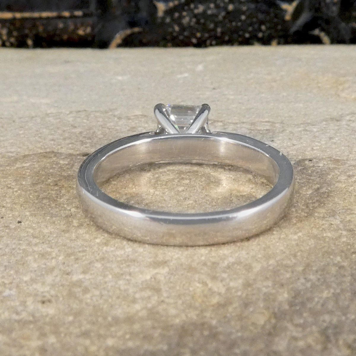 Back view of A Squared Emerald Cut Diamond Solitaire Engagement Ring in a four claw setting with a chunky Platinum band and modern feel.