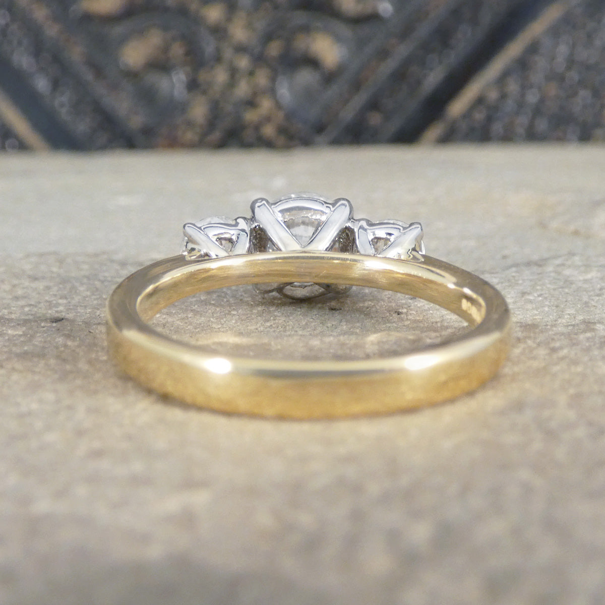 Gold ring with three diamonds on a textured surface
