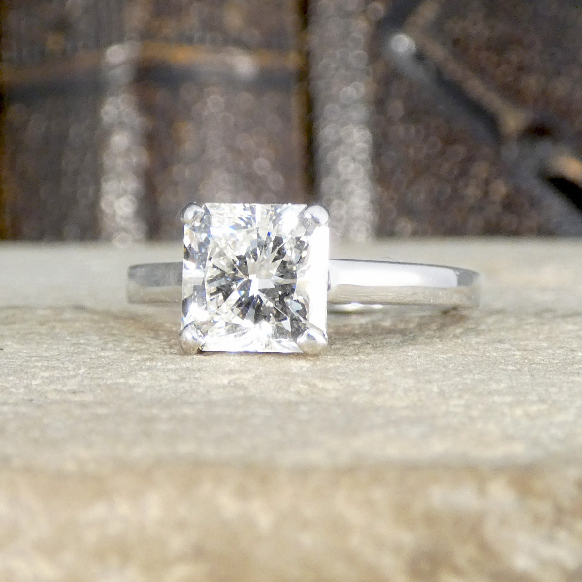 Diamond ring on a textured surface with a blurred background showing clear and bright stone.