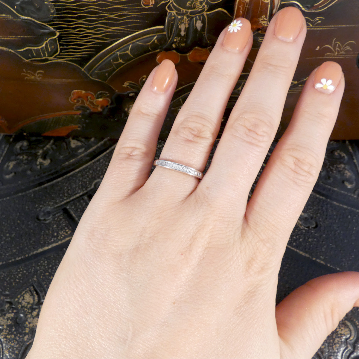 Hand wearing a diamond half eternity ring with a decorative background