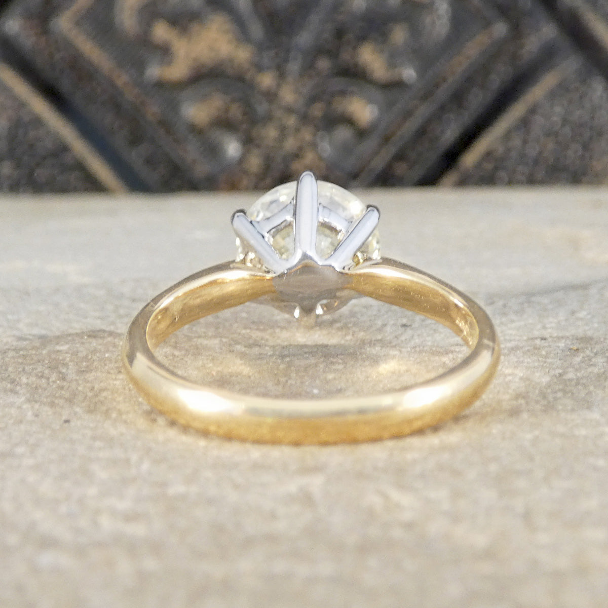 Gold ring with a clear gemstone on a textured surface