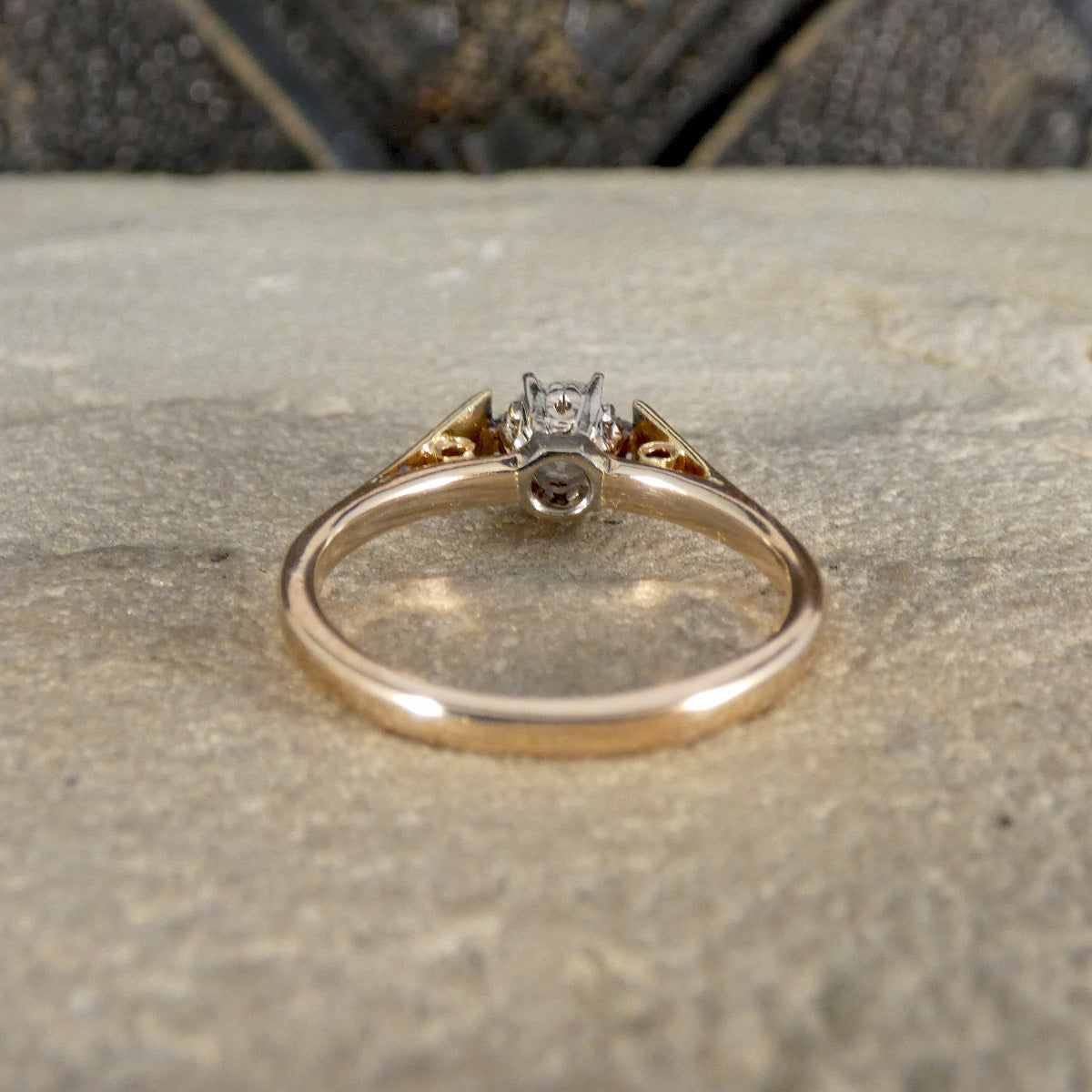 Gold ring with a diamond on a stone surface