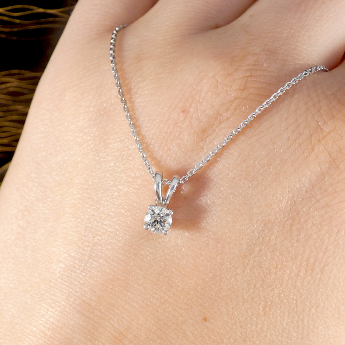 white gold necklace with a diamond pendant on he back of a hand