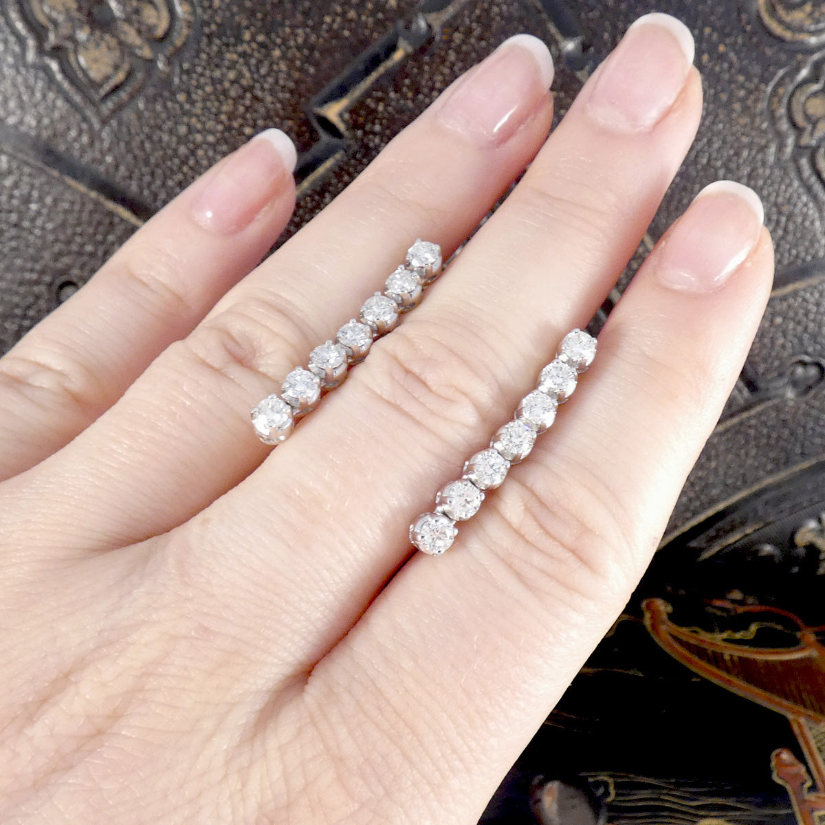 A pair of diamond earrings shown on the hand for size reference.