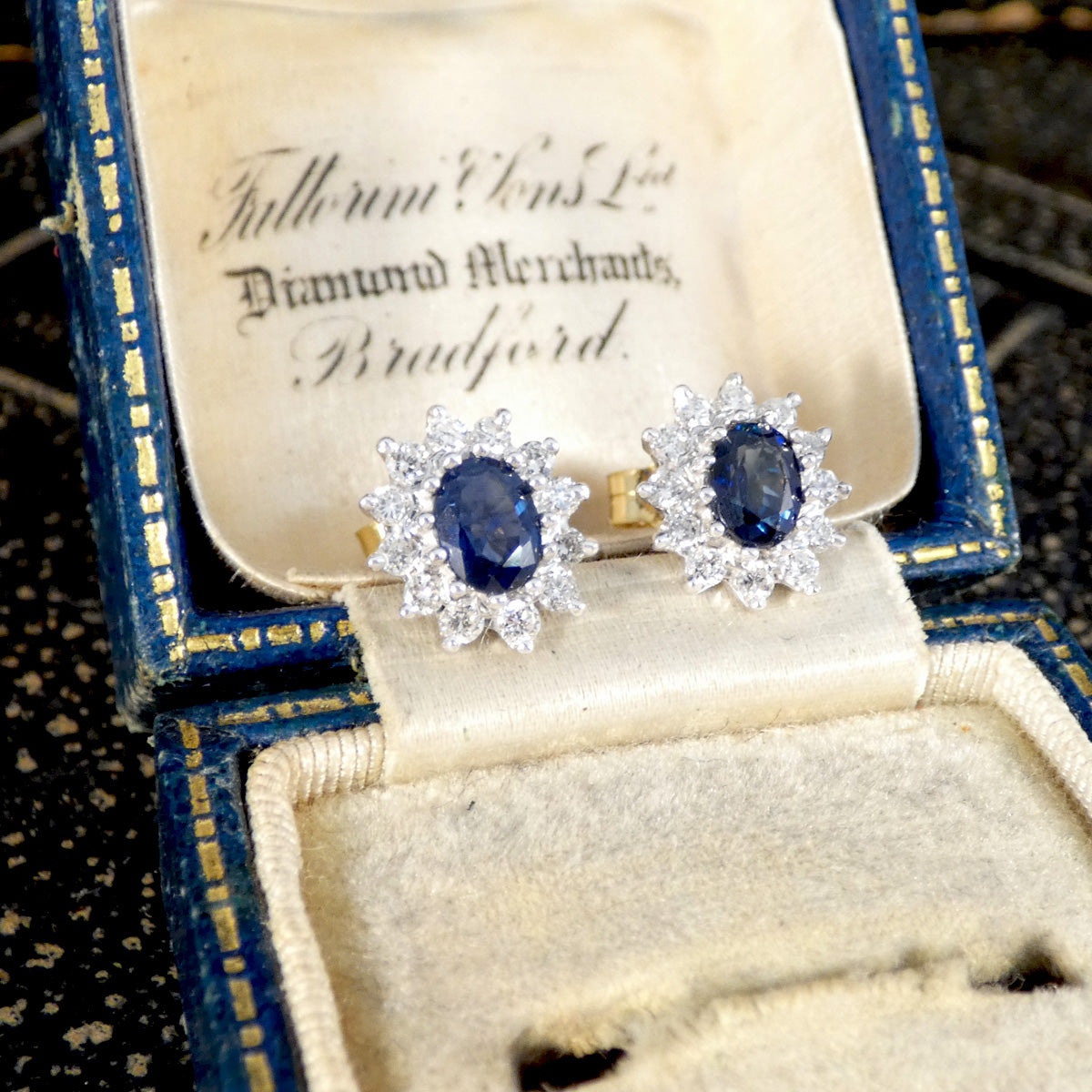 Pair of diamond earrings with blue gemstones in a vintage box