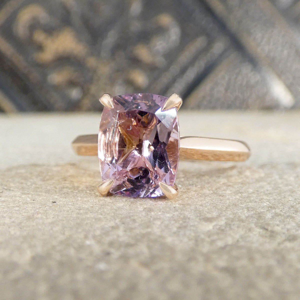 Ring with a pink/purple gemstone on a textured surface