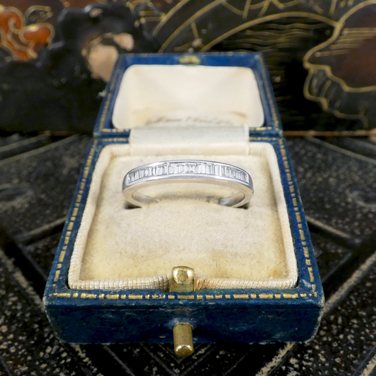 Diamond ring with diamond accents in a blue velvet box on a textured surface