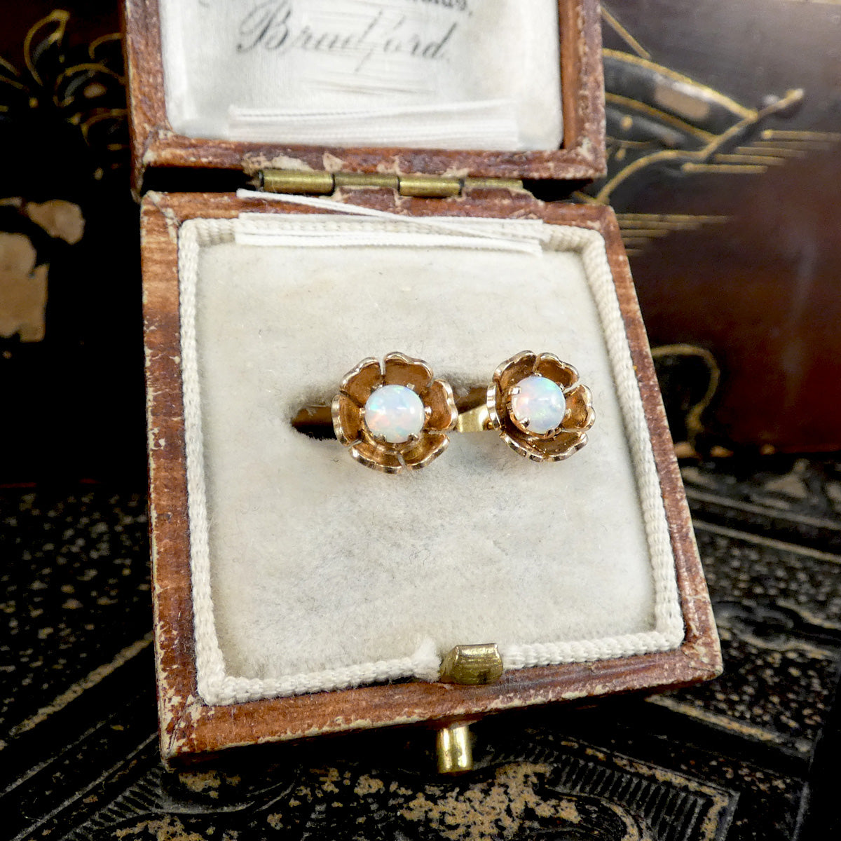 Pair of gold earrings with opal stones in a wooden box