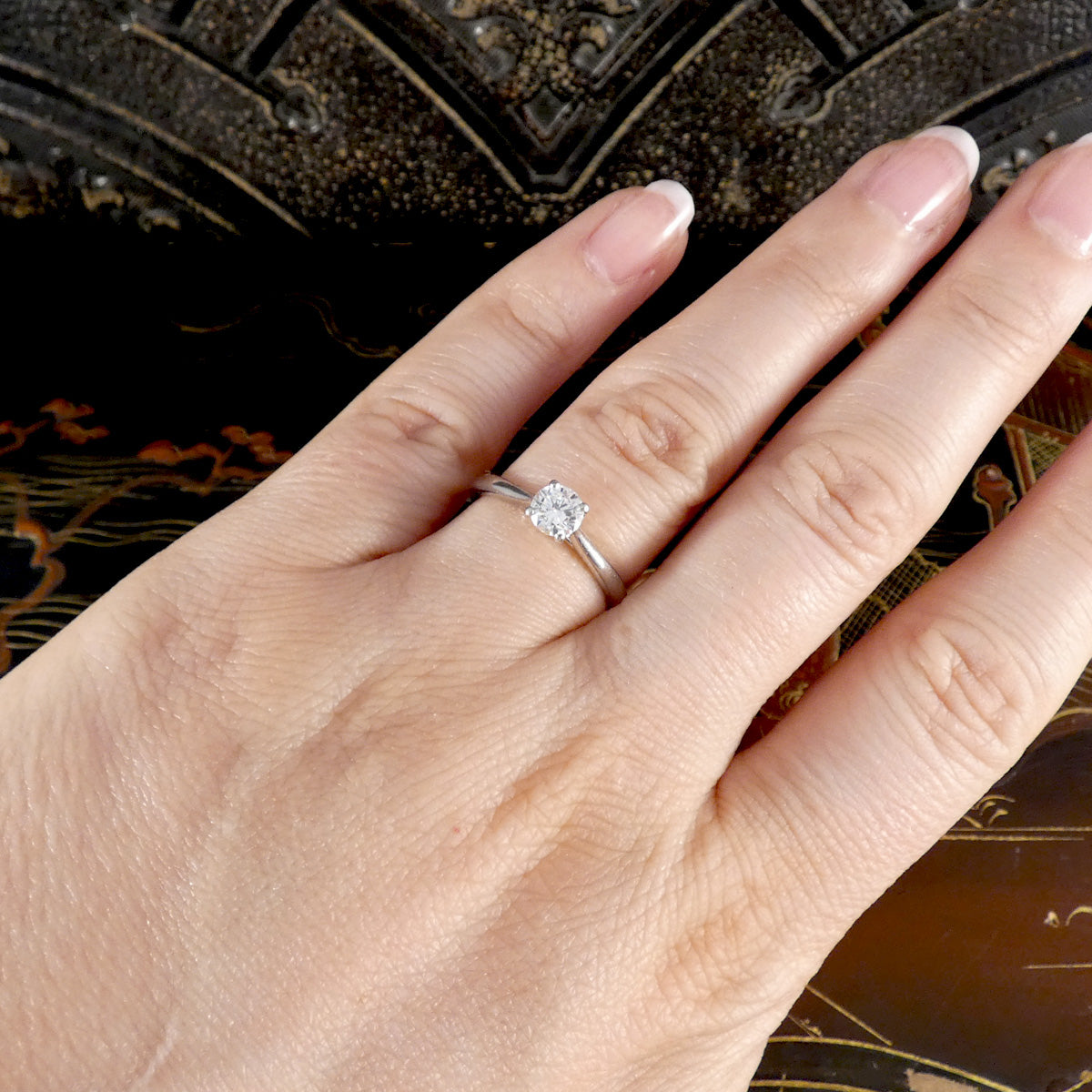 Diamond solitaire engagement ring shown on the hand.