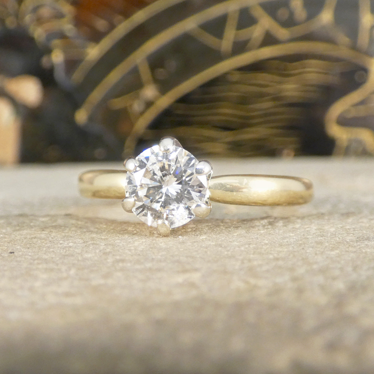 Gold ring with a solitaire diamond on a textured surface
