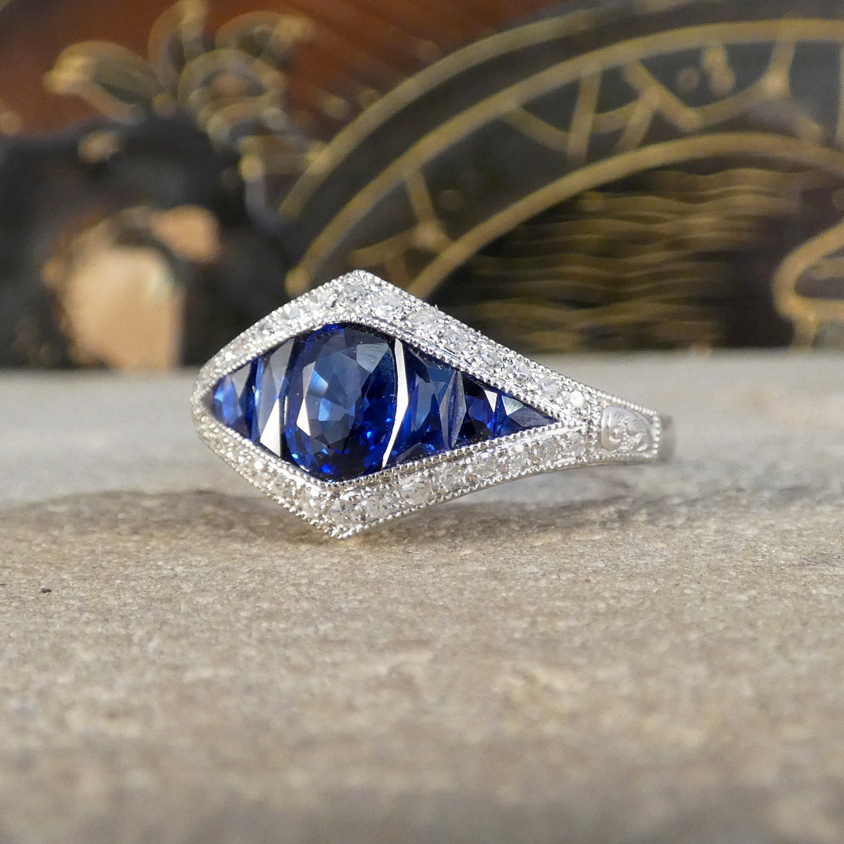 A gorgeous Art Deco style Sapphire and Diamond cluster ring in Platinum. The Sapphires show a beautifully bright and alluring blue.