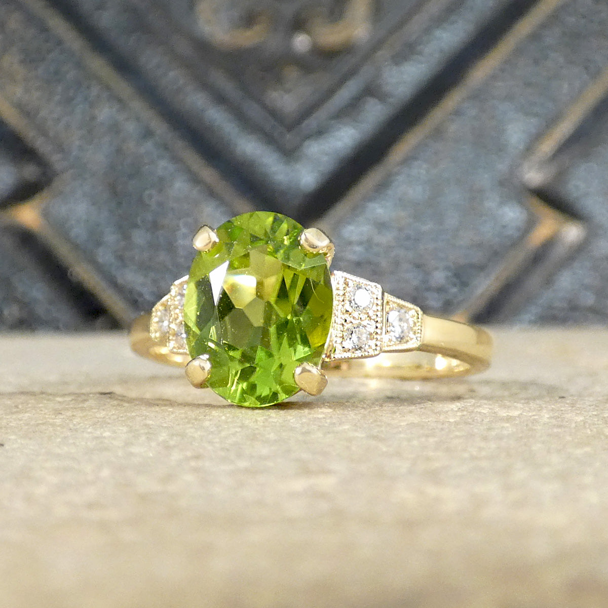 Art Deco style peridot ring set with three Diamonds on each shoulder graduating with two set first then staged down to one.