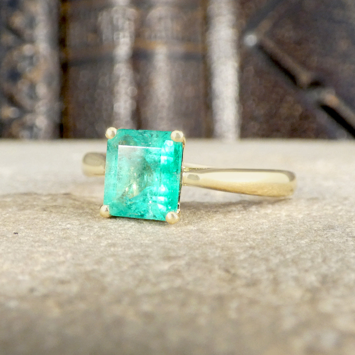 Gold ring with a green gemstone on a textured surface