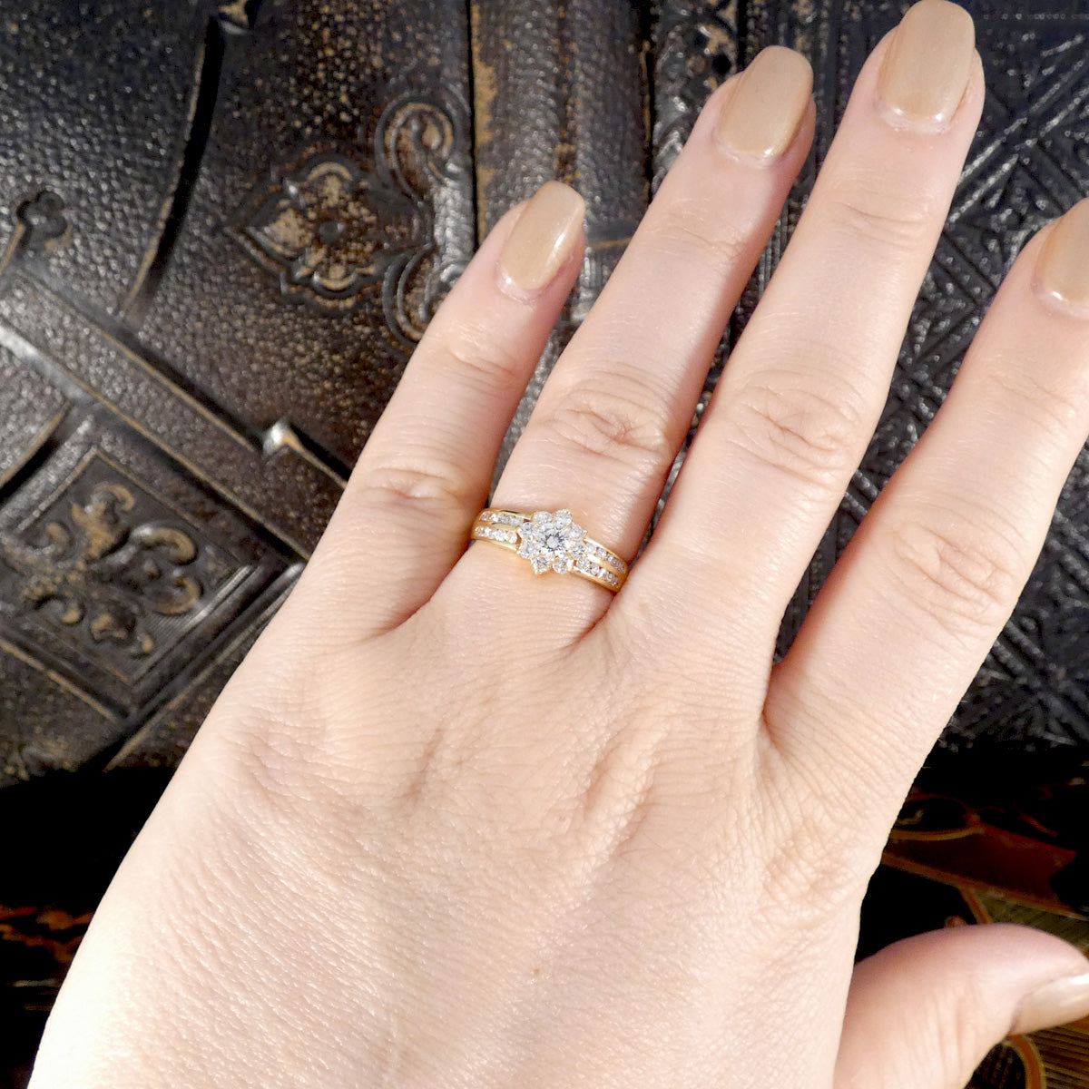 Diamond cluster ring in 18ct yellow gold with a floral-inspired design and split diamond-set shoulders, shown worn on a hand for scale and fit.